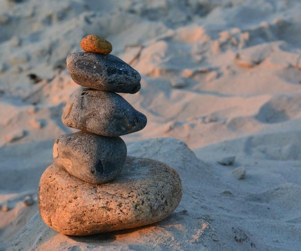 Balanced stones stack on a serene beach at sunset.