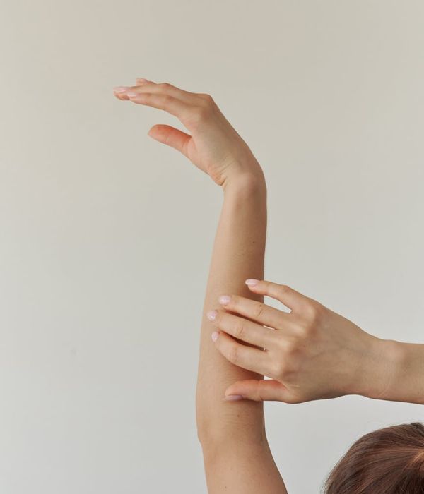 Woman in a peaceful yoga pose against a dark background with magenta light.